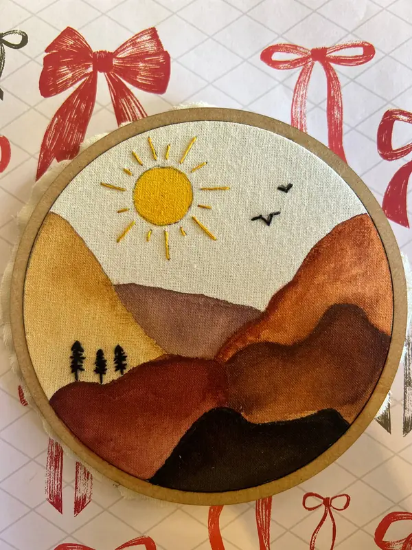 Paisagem de sol e montanhas bordada no bastidor