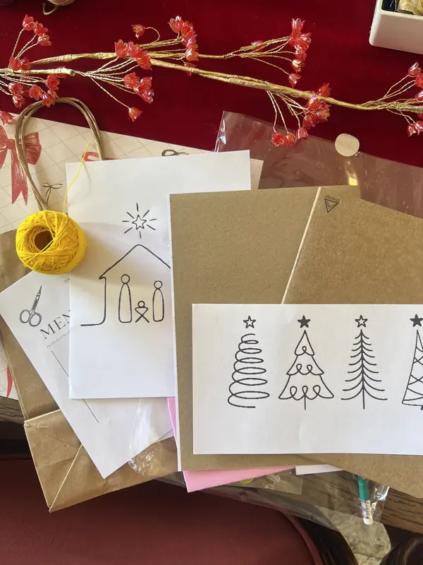 Cartões de Natal ilustrados e novelo de linha sobre a mesa do ateliê